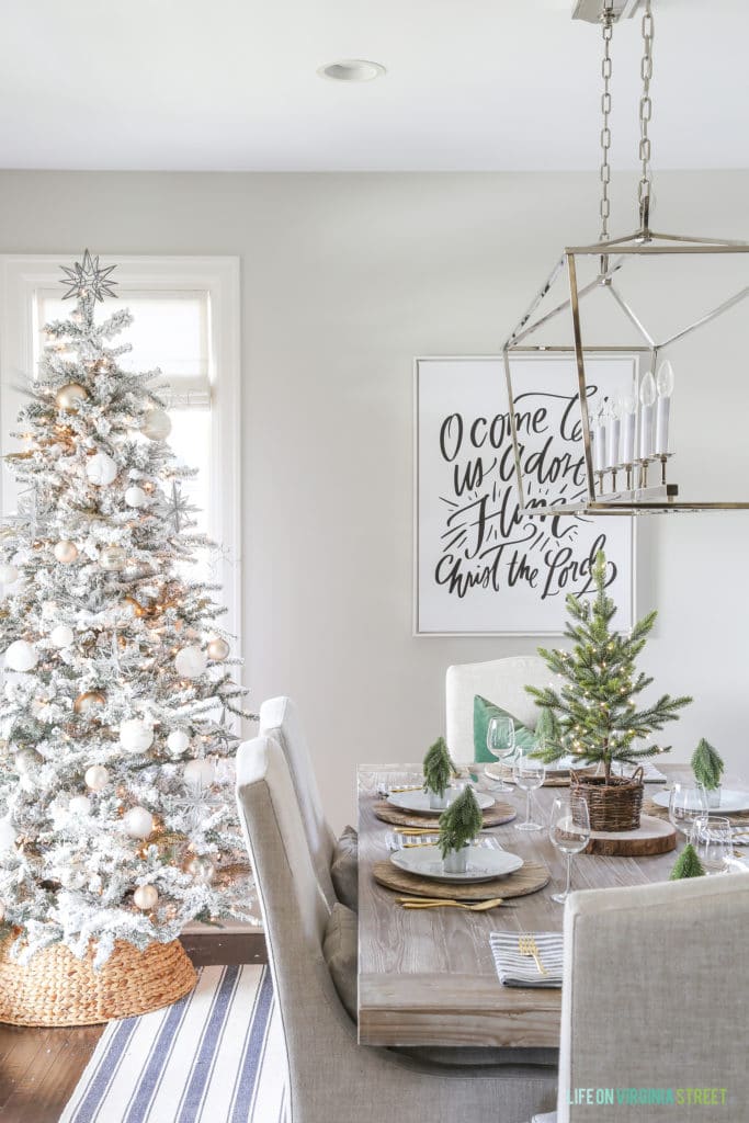 flocked Christmas tree with woven tree collar in a dining room.