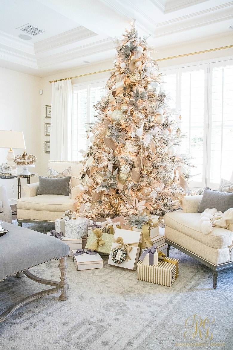 ornately decorated flocked Christmas tree with sitting chairs and unopened gifts beneath it.