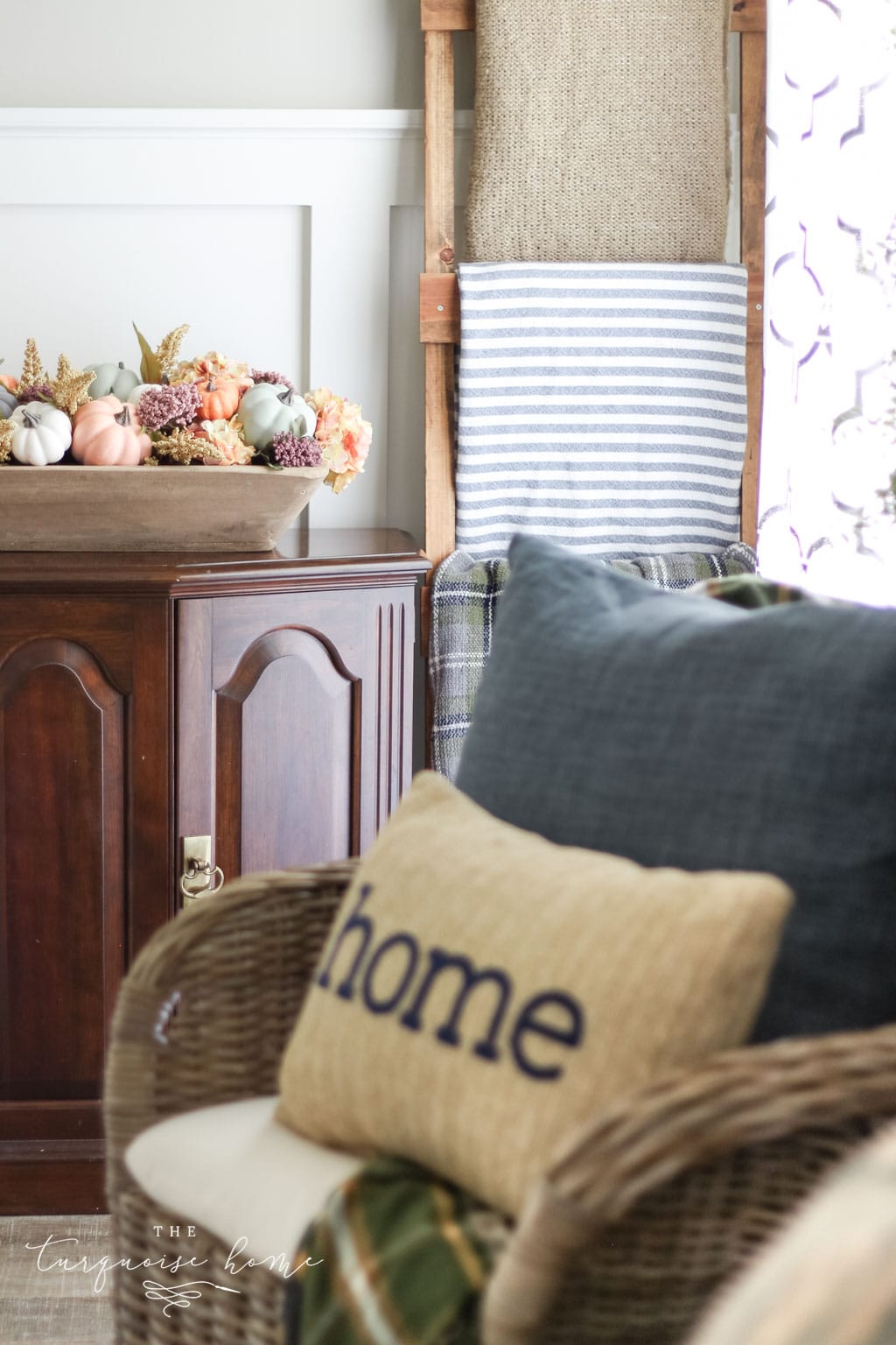 Fall pumpkin centerpiece with home pillow and blanket ladder.