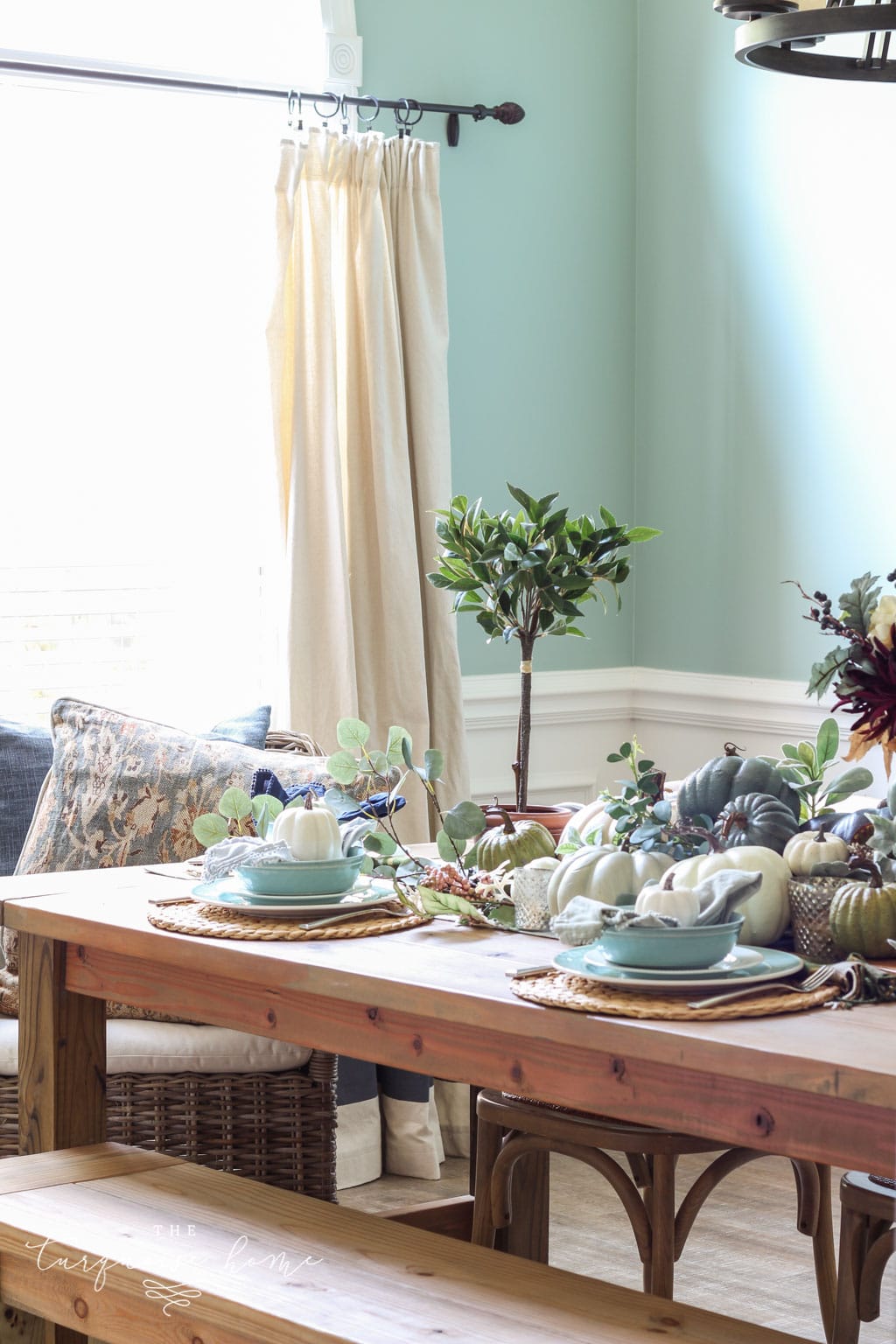 Pumpkins and Greenery Fall Tablescape with bay leaves in a pot and fall floral arrangement.