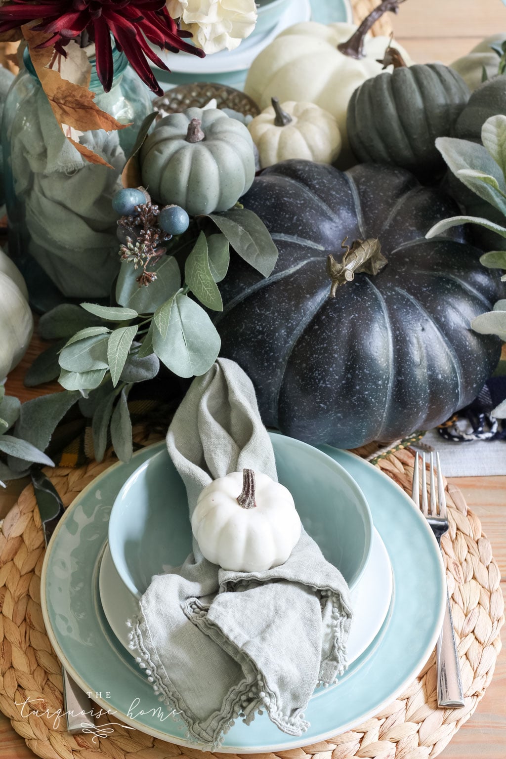 Pumpkins and Greenery Fall Tablescape with bay leaves in a pot and fall floral arrangement.