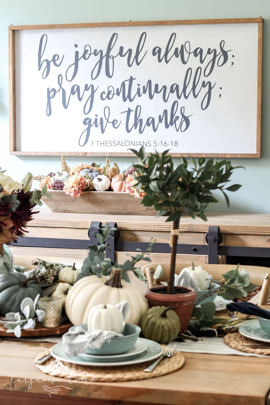 Pumpkins and Greenery Fall Tablescape with bay leaves in a pot and fall floral arrangement.