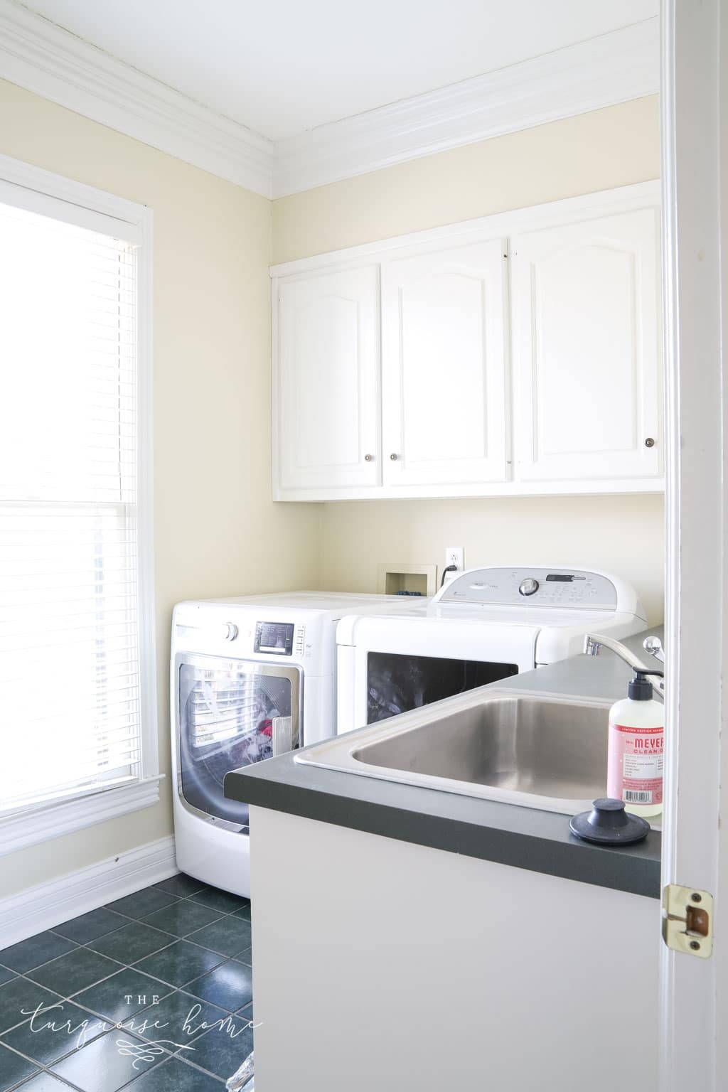 Laundry room with lots of storage, hunter green tiles on the floor and hunter green countertops.