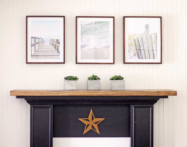 three framed beach image hanging over a mantel with three small potted plants