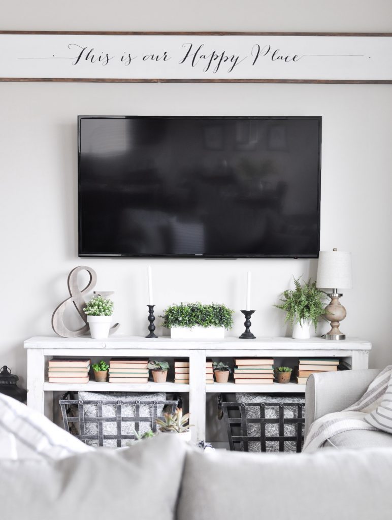 summer fireplace decor of greenery, candles, and a lamp that fit under a TV