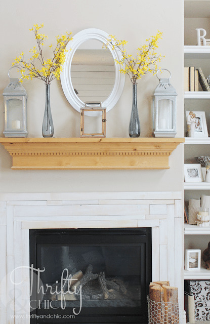 simple mantel decor consisting of three lanterns and two tall bottles with blooming branches