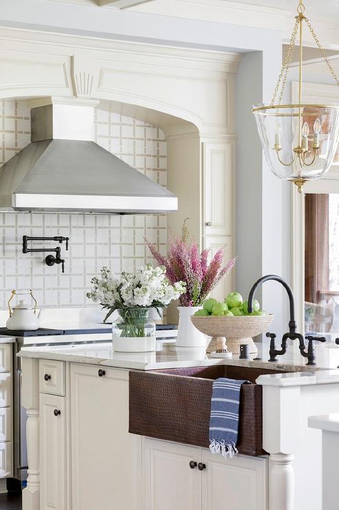 hammered copper farmhouse sink in a beautiful white kitchen