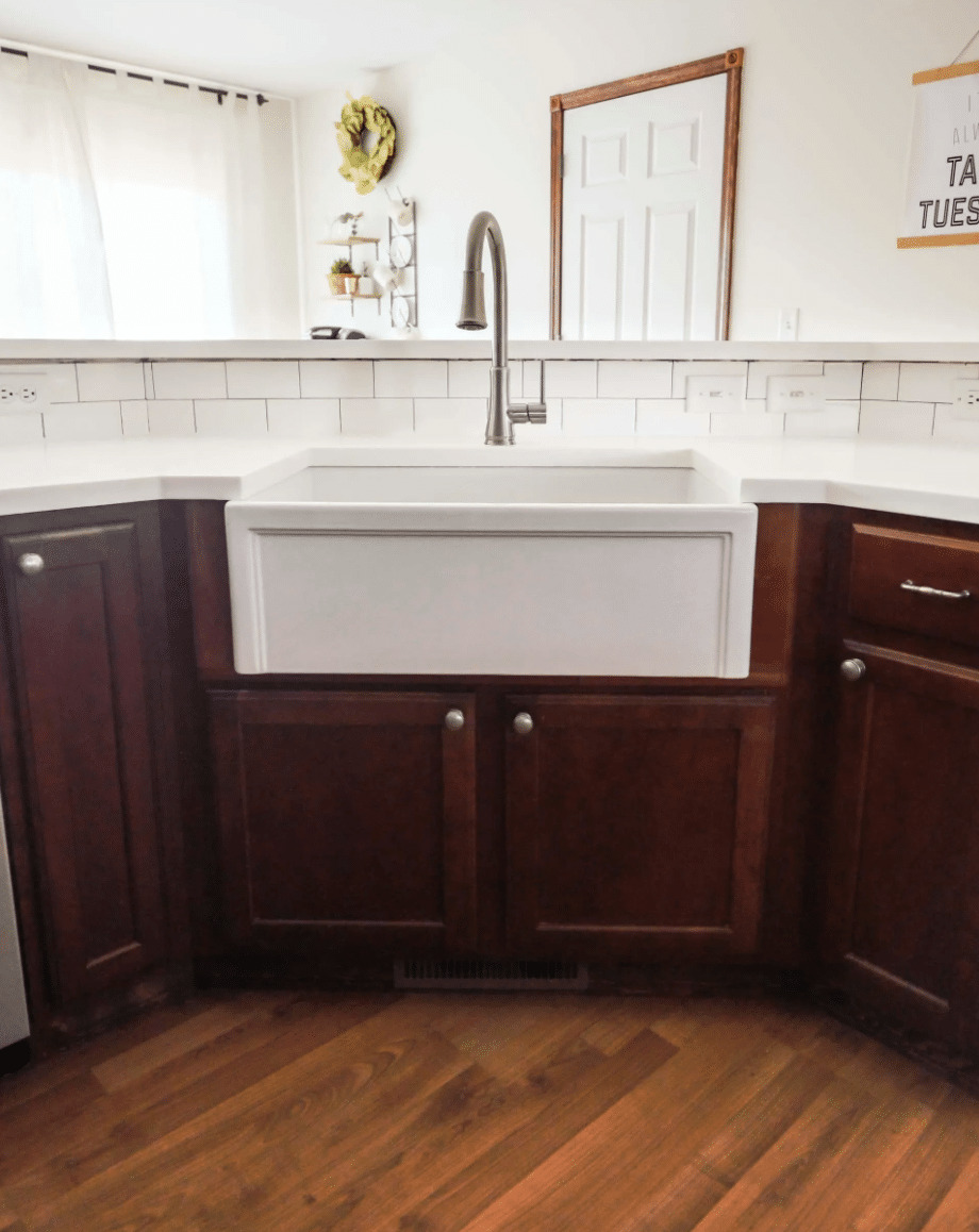 white farmhouse sink with dark wood cabinets
