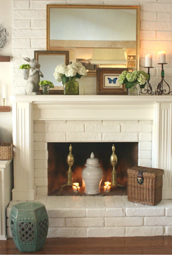 a mix of old and new in spring mantel decor with antique pieces and flower blooms