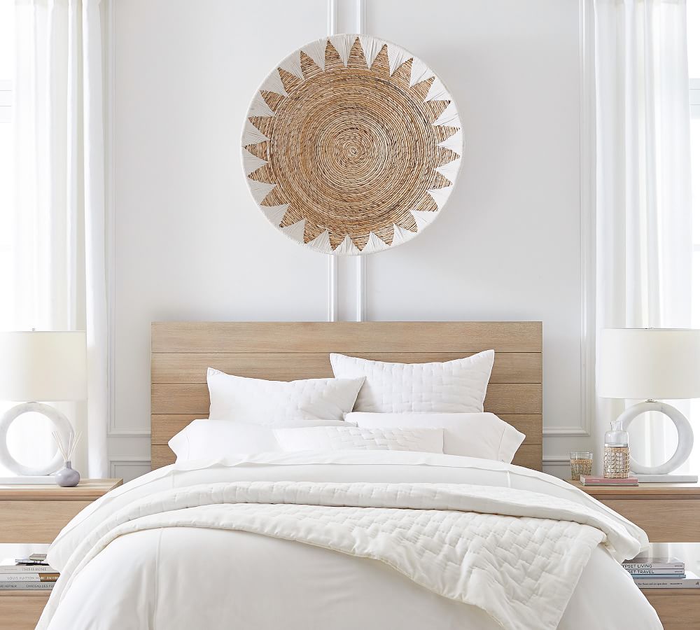 a woven basket hanging on the wall above a bed