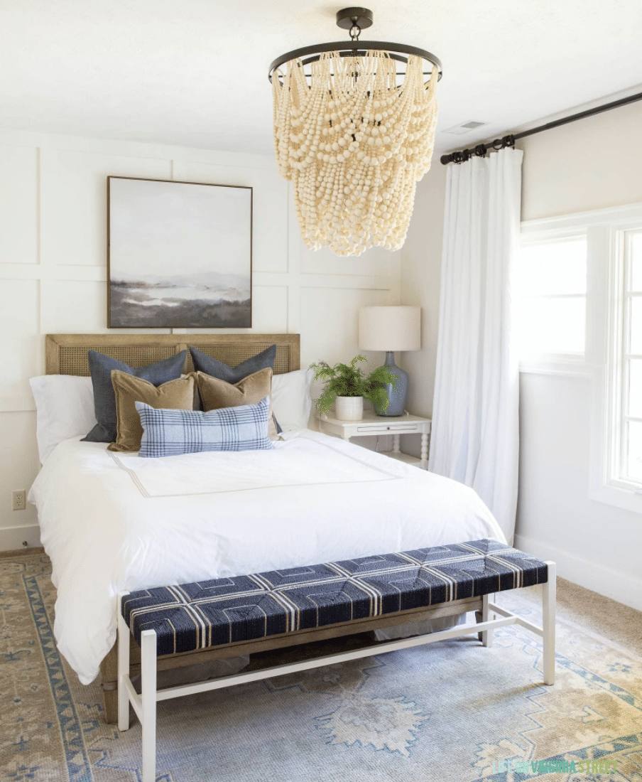 Swiss Coffee painted bedroom with white bedding and statement chandelier