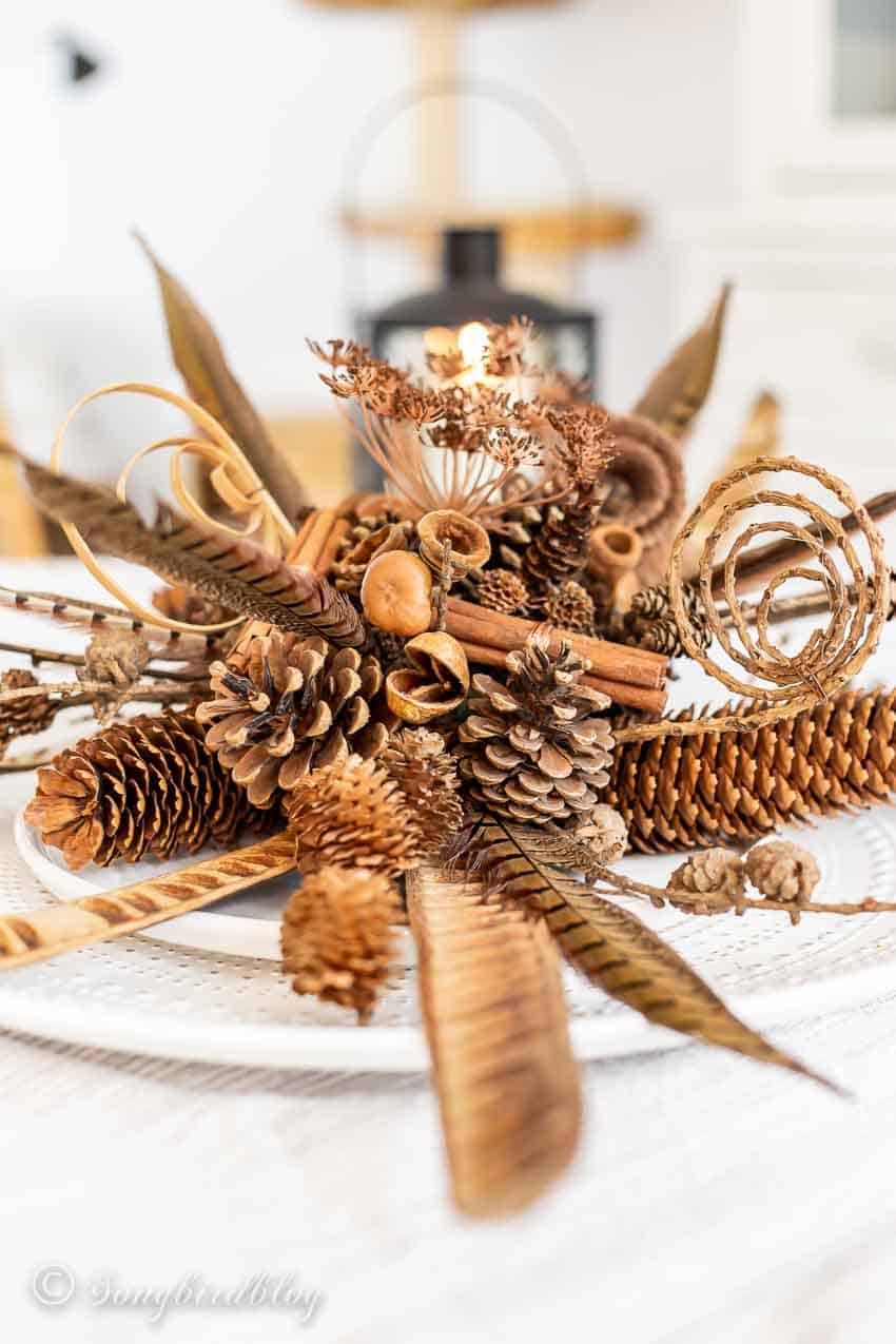 pinecones, cinnamon sticks, feathers, and florals in a fall centerpiece