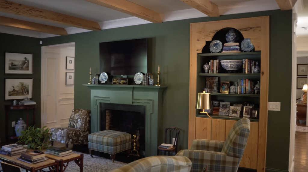Eric Ross' Green Family Room with a mantel and TV above it and built-in wooden bookshelves.