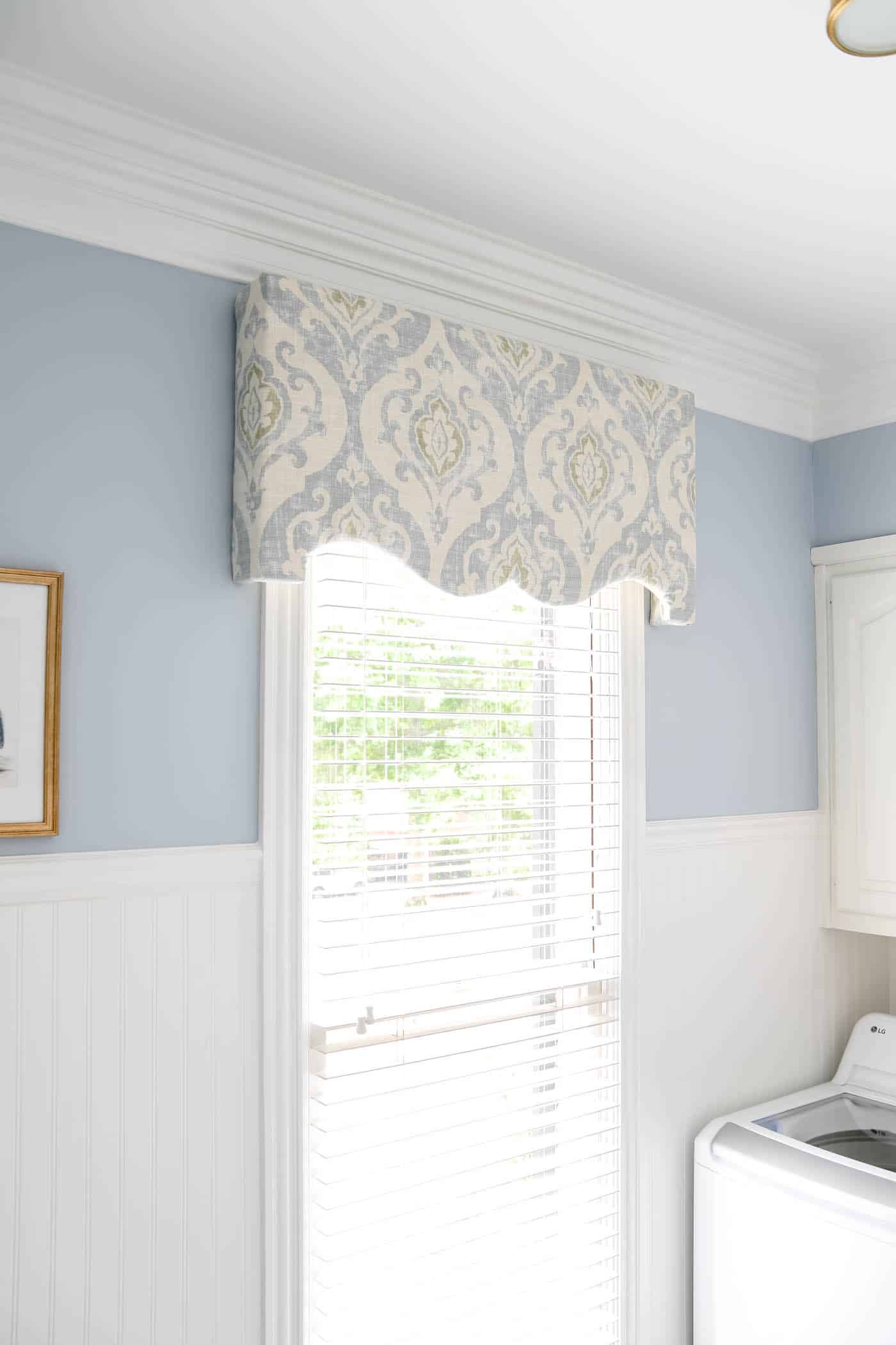 cornice board over a window in a blue and white laundry room