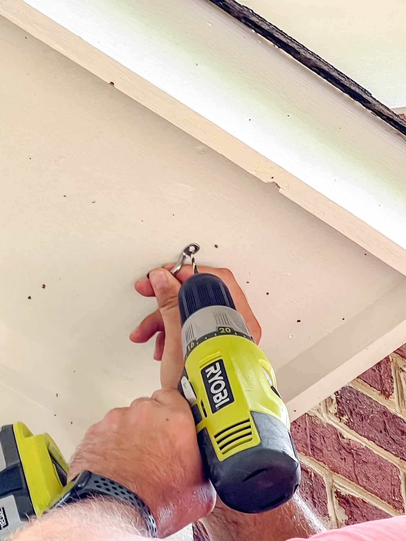 installing string lights with a hook on a side of a house.
