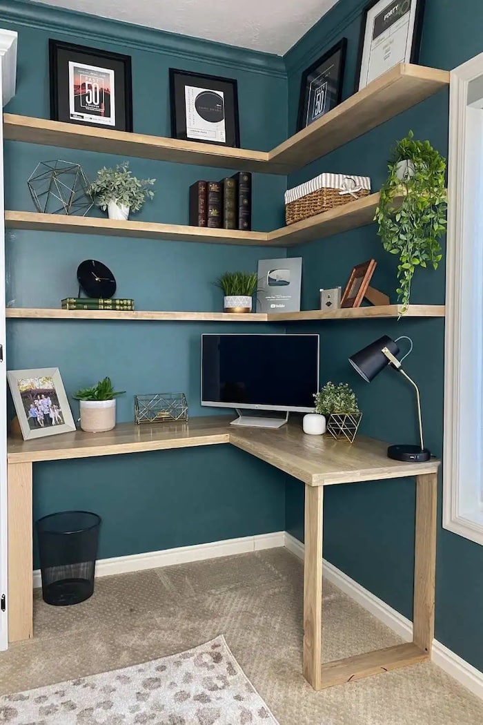 corner of a room with shelving and a desk underneath.