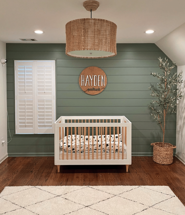 Boy's nursery with green shiplap walls and a modern white and wood crib.