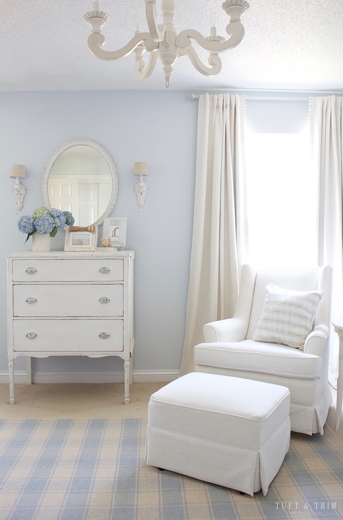 Traditional boy's nursery with blue walls and white glider and ottoman.