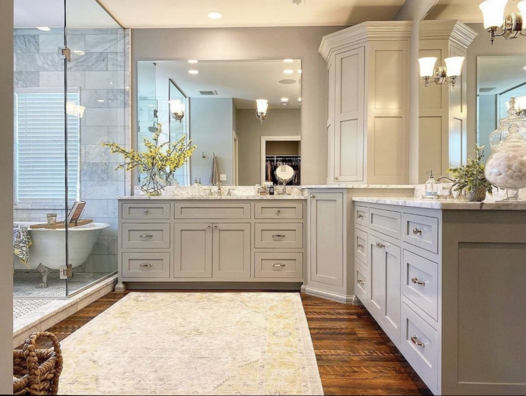 Spacious gray bathroom with clawfoot tub inside the shower and a large area rug on the floor.