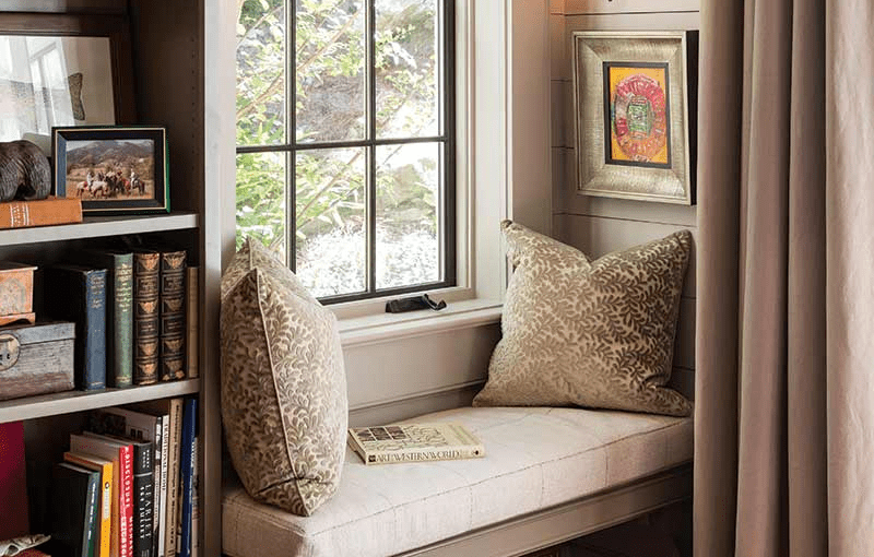 Built-in bench reading corner near a window with plush curtains.