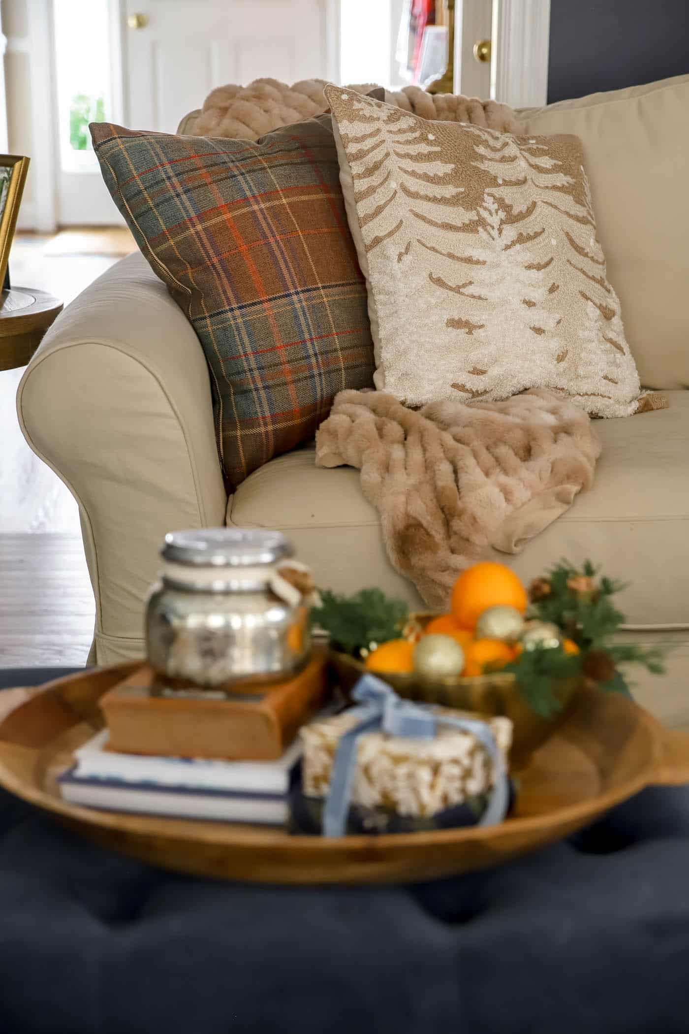 vignette with oranges and books and presents with neutral Christmas pillows in the background.