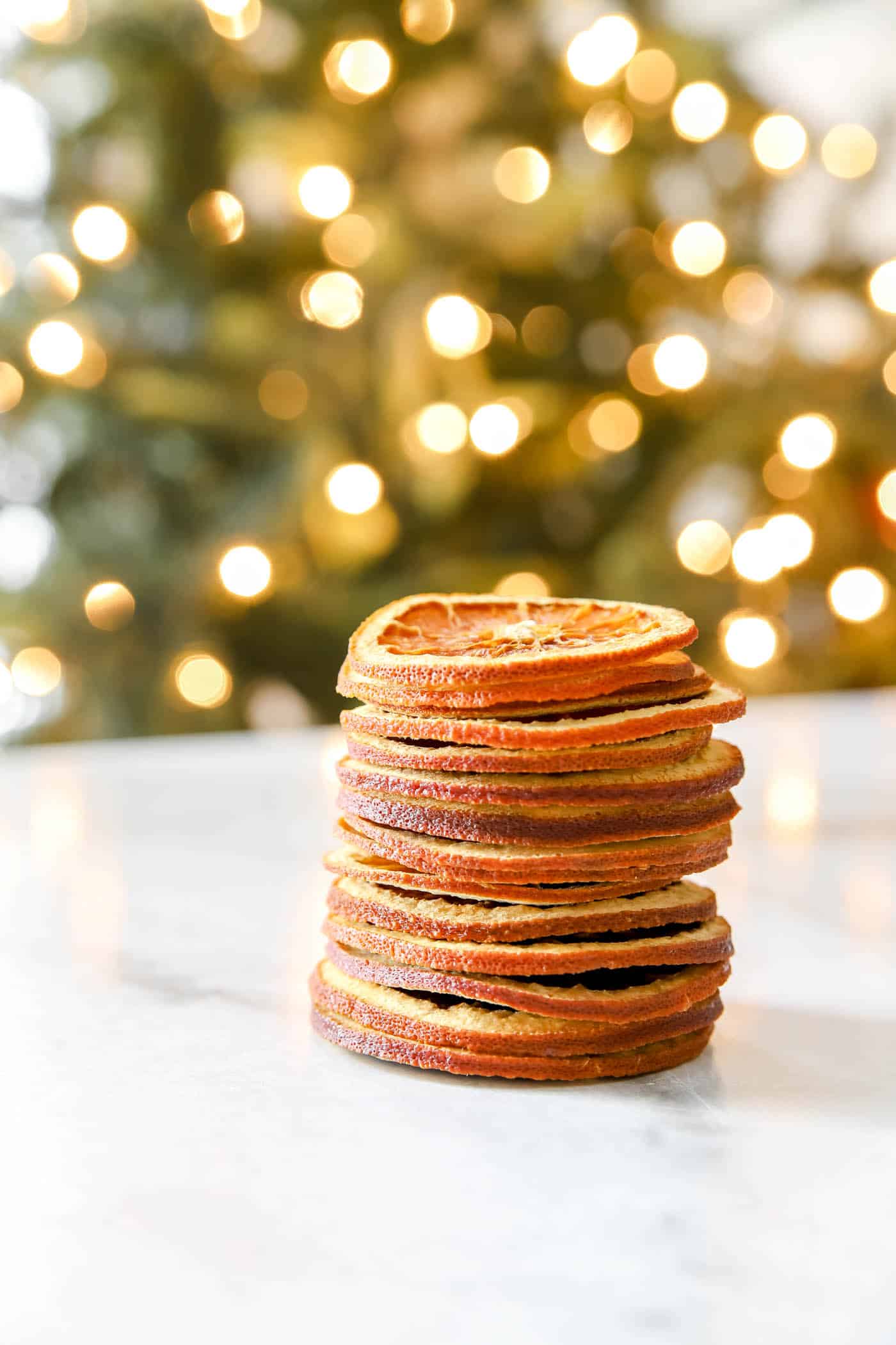 stack of dried orange slices in front of a Christmas tree.