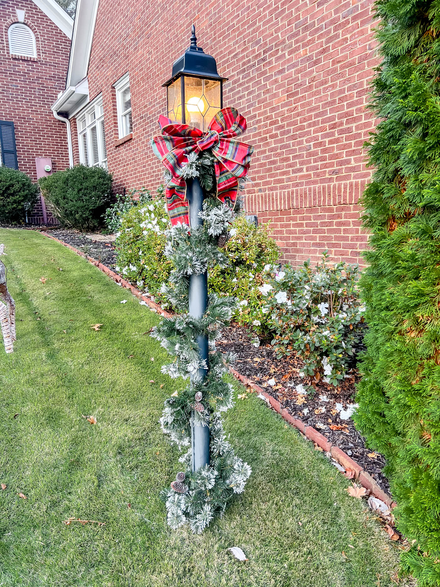 lamppost with holiday garland and red plaid bow.