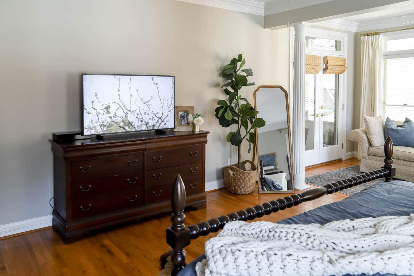 bedroom corner with smaller mirror and large fiddle leaf fig tree.