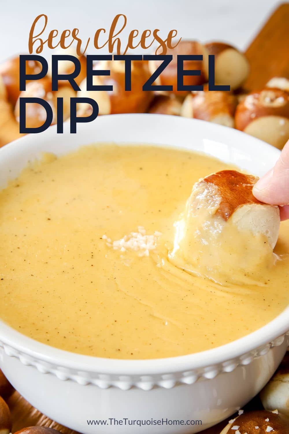 beer cheese dip with a hand dipping a pretzel in it.