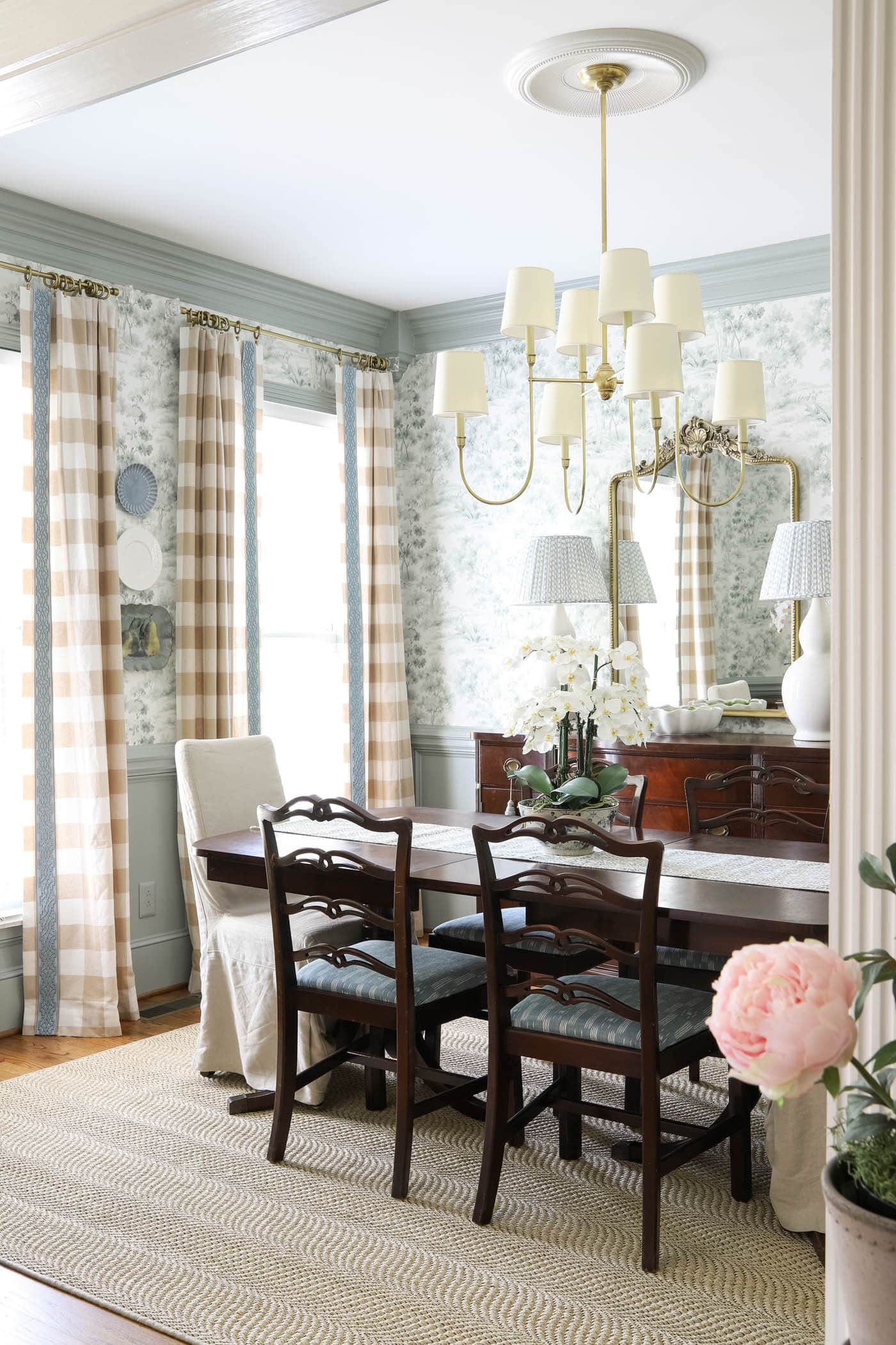 plates on a wall between windows in a formal traditional dining room.