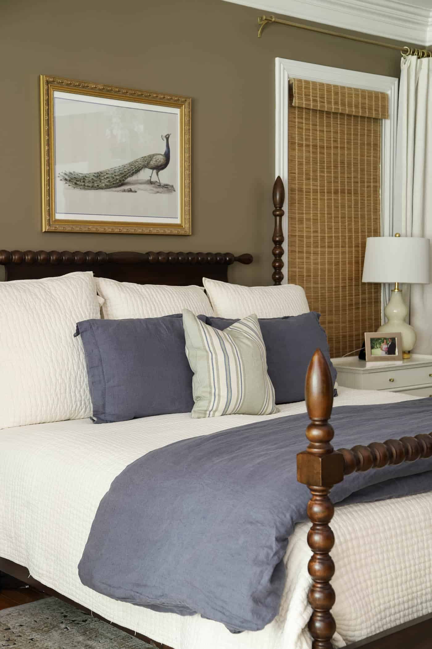 Davenport Tan wall color in a primary bedroom with an ivory quilt and blue bedding.