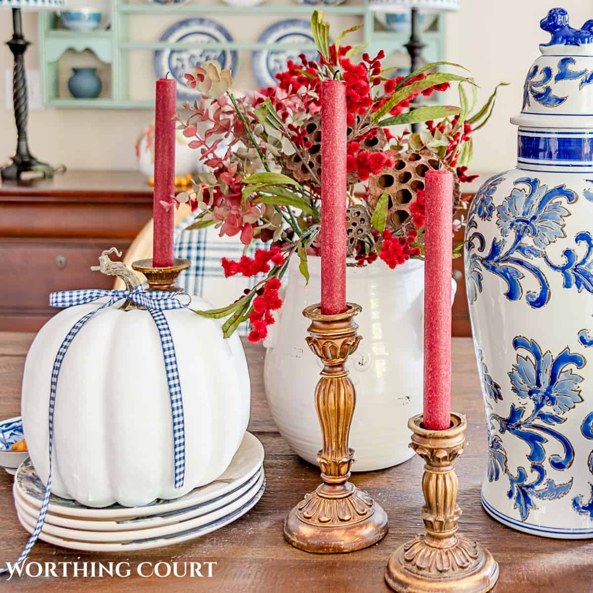 white pumpkin with red candles with wood candlesticks.