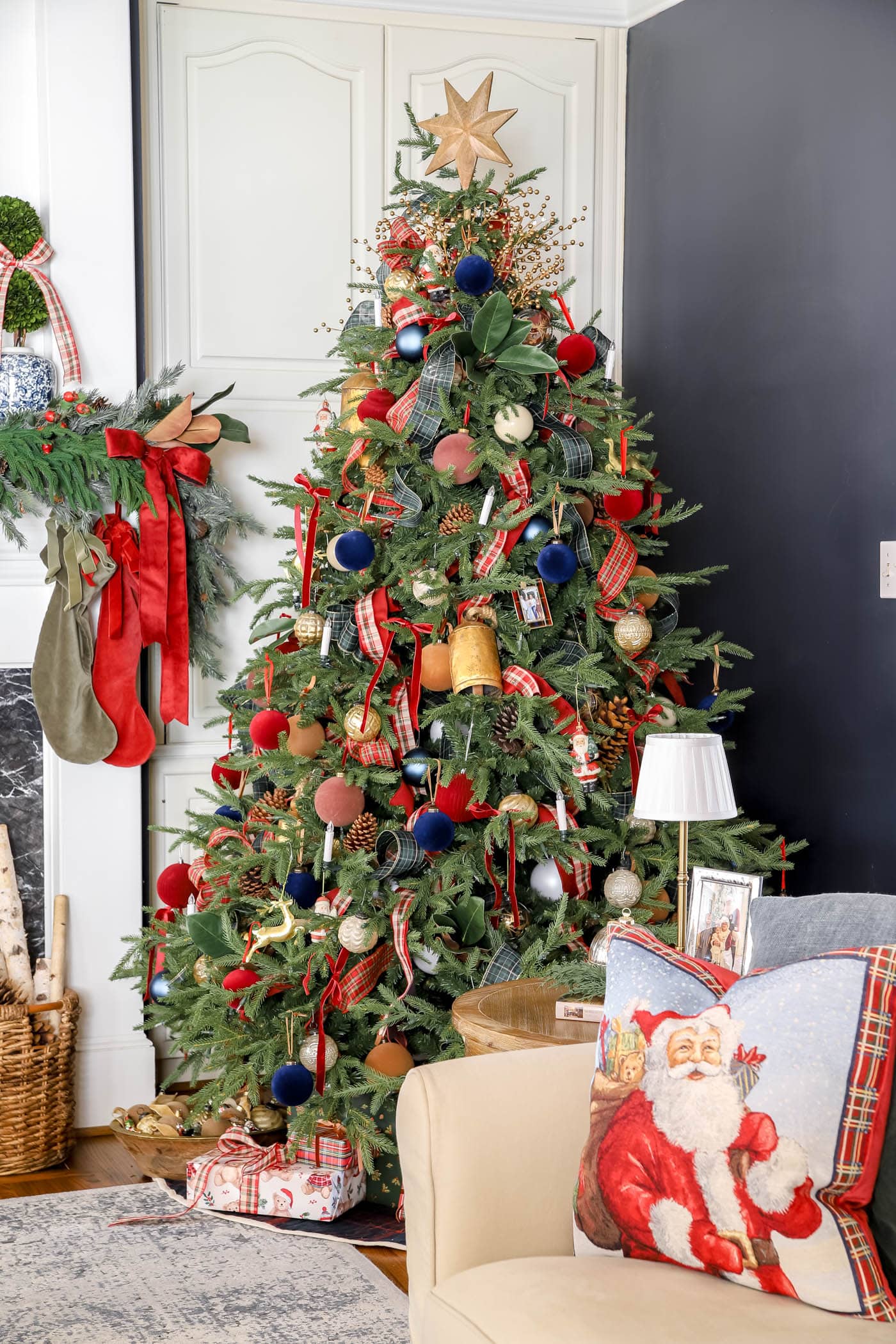 side table with Santa and children in a frame, small cordless lamp and ornament candle with a christmas coffee table book and greenery.