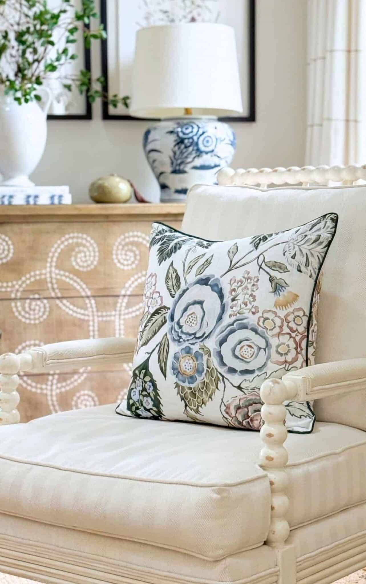 cream upholstered chair in the living room with a blue and white pillow.