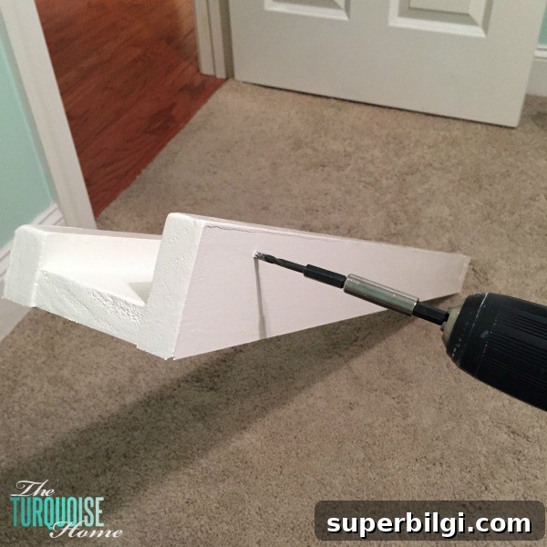 DIY Floating Bookshelf Ledges for Nursery Decor 9 Installing ledges on the wall with screws into studs.