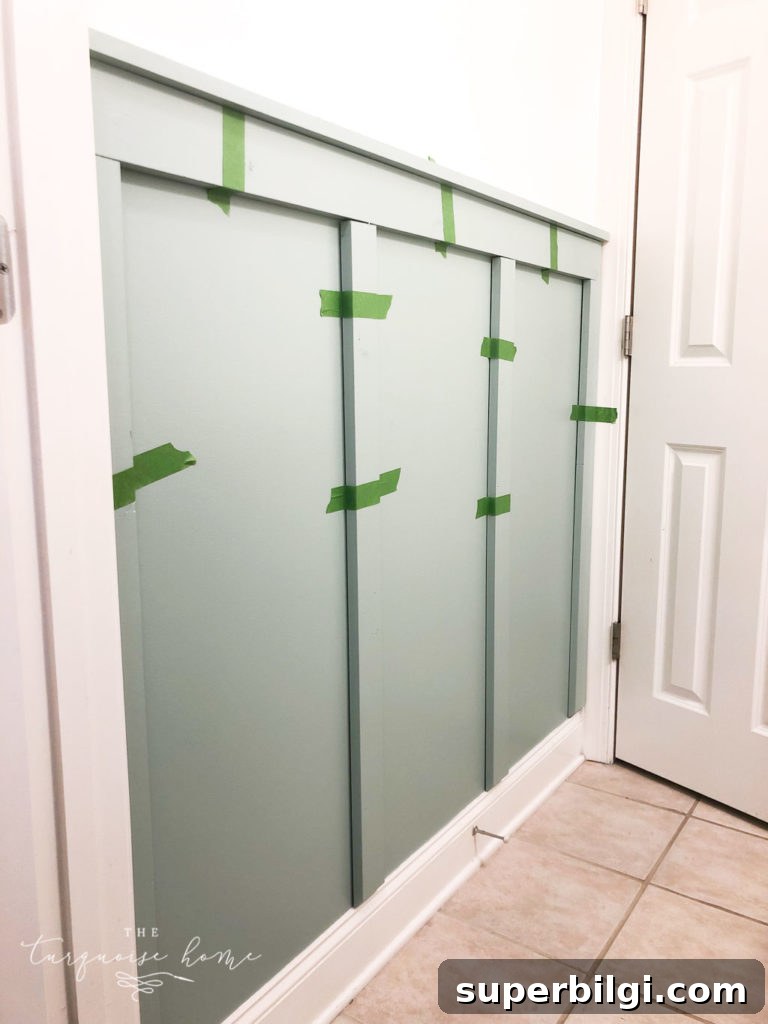How to Install Board and Batten in a Girls' Bathroom 7 Place boards in the wall and hold them up with painter's tape to see where they should go