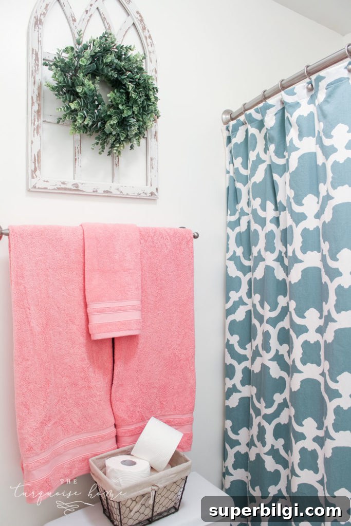 Window arch above the toilet in the girls' bathroom refresh | Use a basket for toilet paper storage and a over-the-toilet cabinet if needed | bathroom makeover | pink towels | antique distressed window frame | eucalyptus wreath
