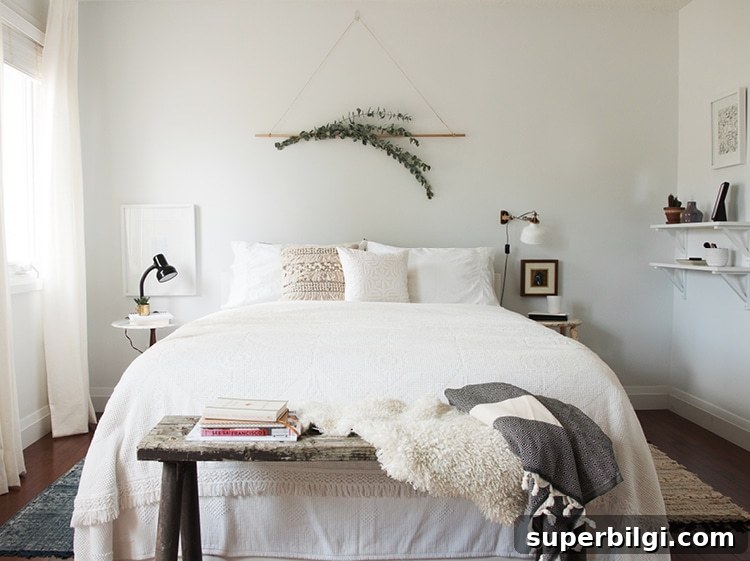 sprigs of eucalyptus hang on the wall above a bed