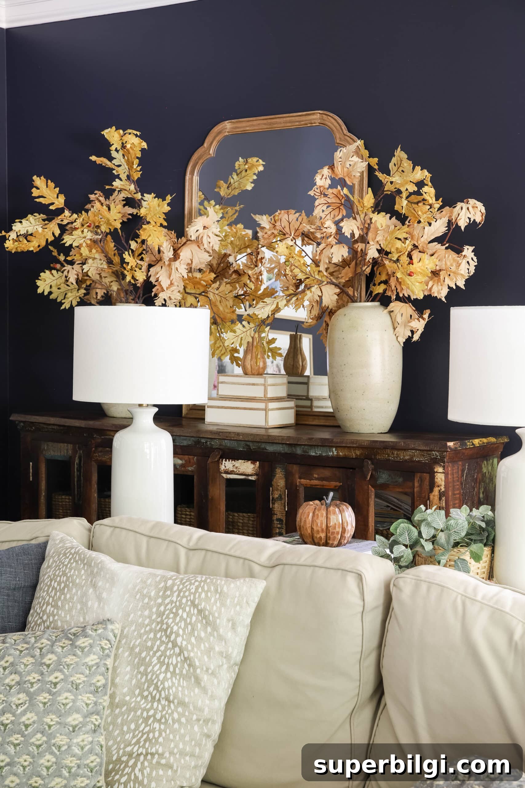 Fall Decorating Ideas to Create a Cozy Home 7 leafy autumn oak stems in earthen vases in a living room with navy walls.
