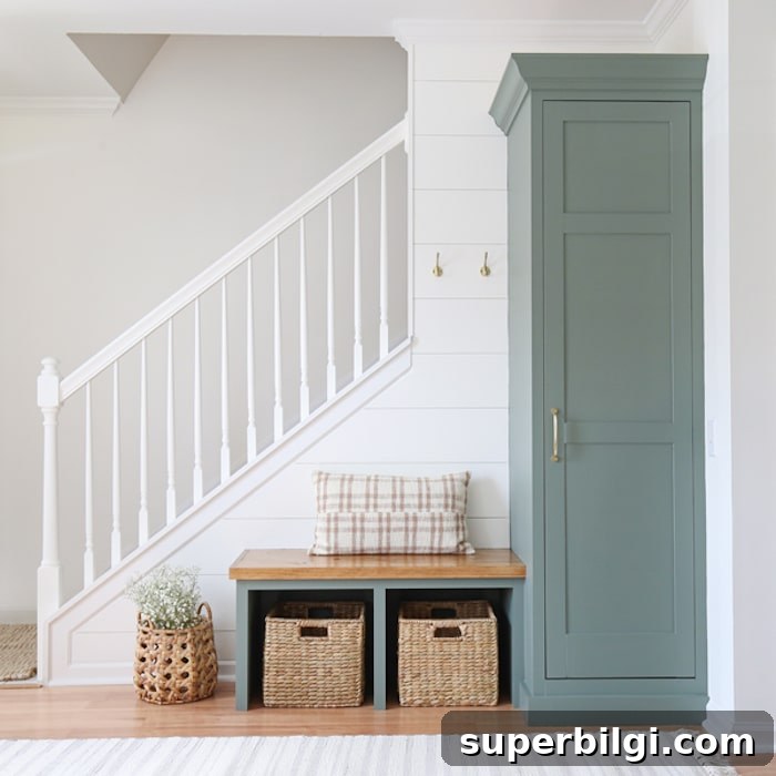 entryway with shiplap white walls, stairwell rails and built-in cabinet and bench painted Sherwin Williams Retreat.