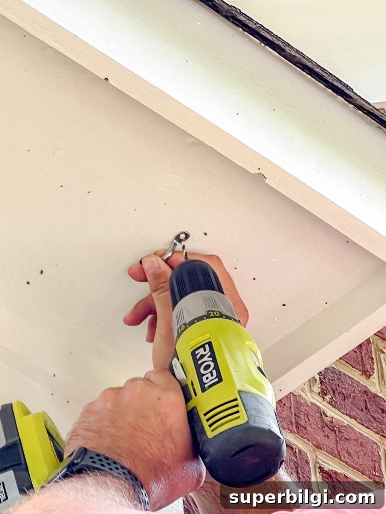 Hang Outdoor String Lights: DIY Patio and Backyard Tips 10 installing string lights with a hook on a side of a house.