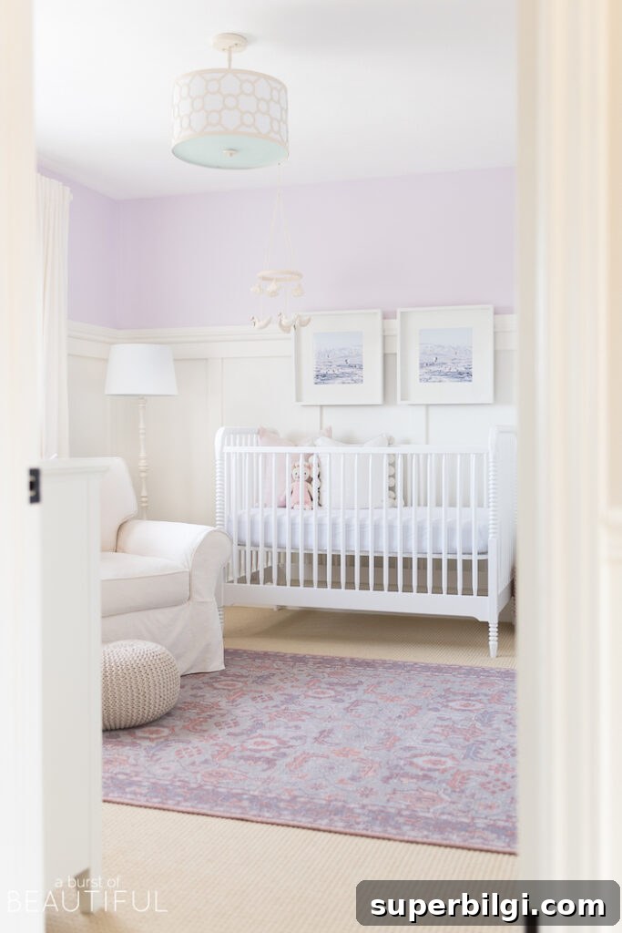 20 Nursery Paint Colors and Accent Wall Ideas for Baby Rooms 7 purple wall color in nursery with white crib and white arm chair.