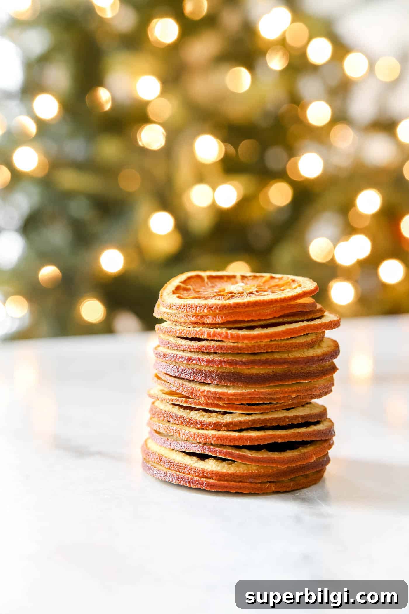 How to Dry Orange Slices for Crafts and Decorations 9 stack of dried orange slices in front of a Christmas tree.