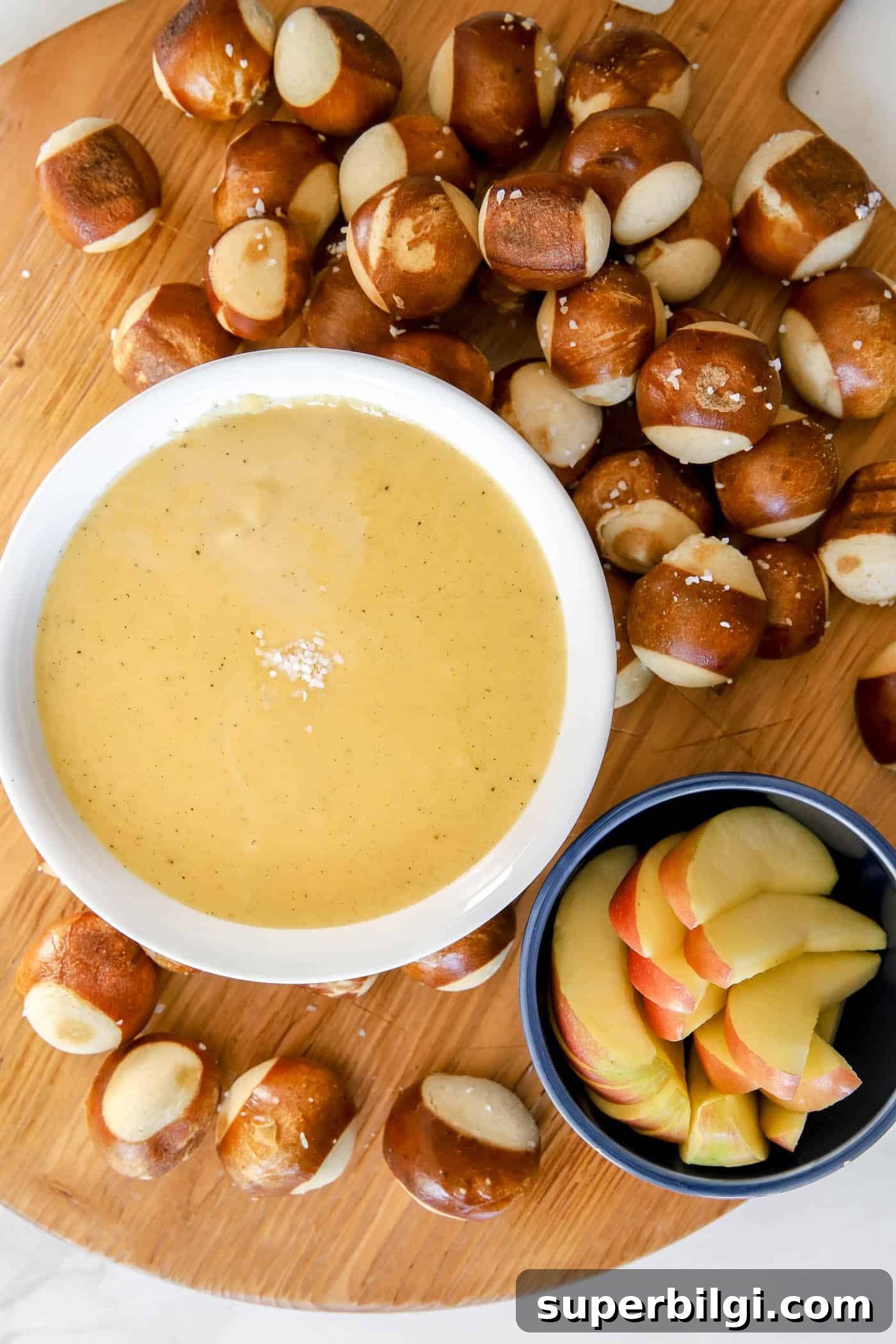Creamy Beer Cheese Dip Recipe for Pretzels 5 serving beer cheese pretzel dip on a charcuterie board with pretzel balls and apple slices.