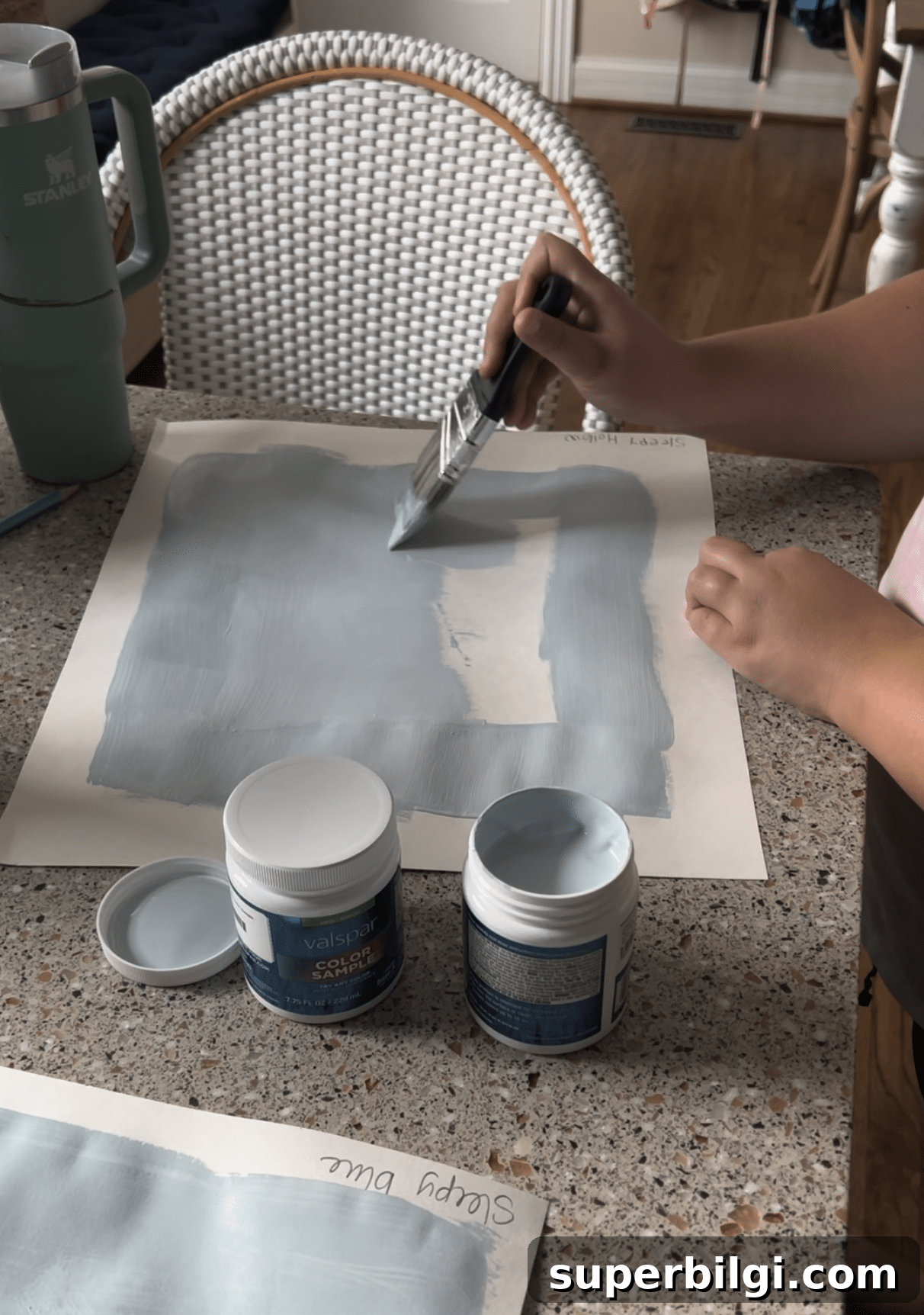 painting a blue paint swatch on a poster board.